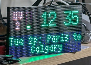 A panel of LEDs, displaying a UV index in the top left corner reading 2 with a small bar chart out of 10, the time 12:35, and the text Tue 2p Paris to Calgary